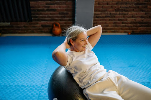 Elderly woman uses exercise ball to help improve pelvic health.