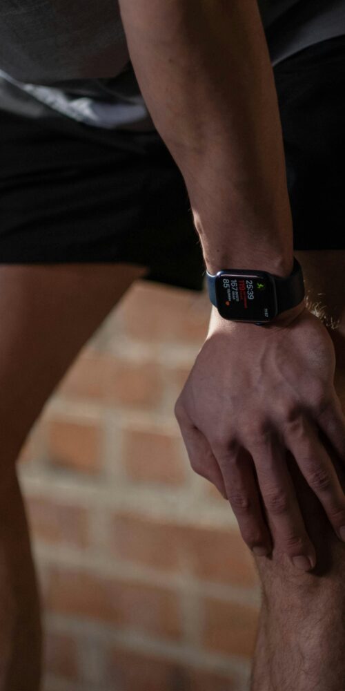 Individual resting hands on their knee after activity, highlighting knee rehabilitation and physical therapy exercises for recovery and strength.