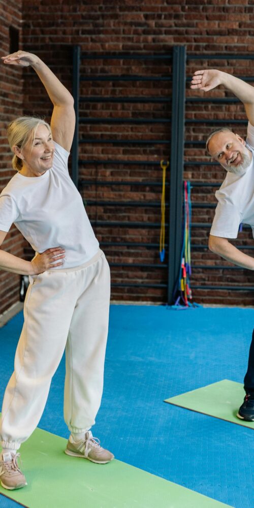 Two elderly patients stretching for a personalized physical therapy routine.