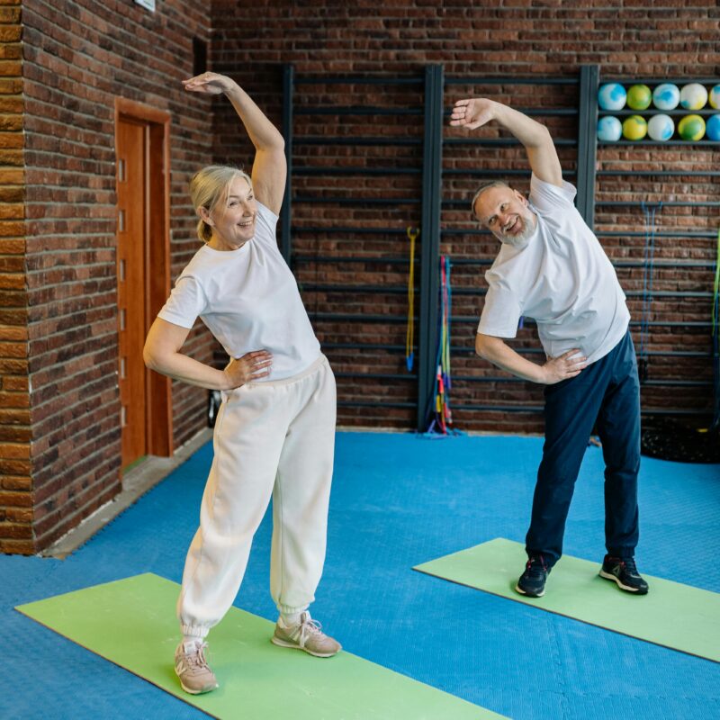 Two elderly patients stretching for a personalized physical therapy routine.