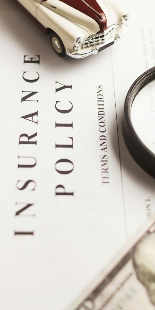 An insurance policy and money sit on a desk