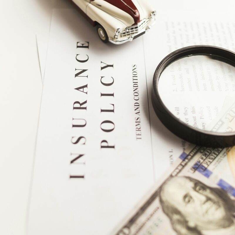 An insurance policy and money sit on a desk
