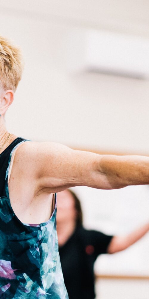 A senior woman in an athletic tank top does an aerobic exercise in a physical rehabilitation center.